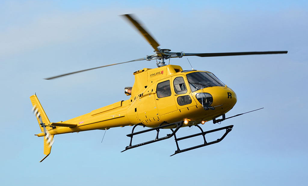 Yellow Airbus H125 flying in the sky