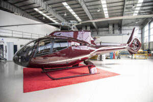 Maroon Gold Airbus EC130 T2 in Pacific Crown Helicopters hangar
