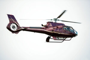 Maroon Gold Airbus H130 Flying in the sky