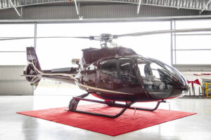Maroon Gold Airbus EC130 T2 in Pacific Crown Helicopters hangar