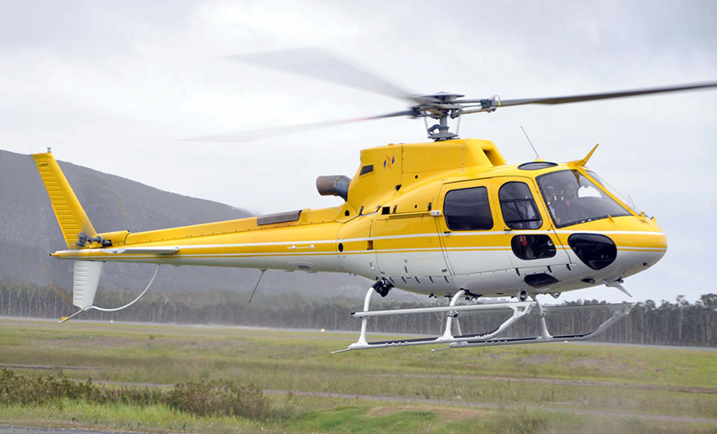 Airbus AS350 B3e helicopter flying in front of Mount Coolum